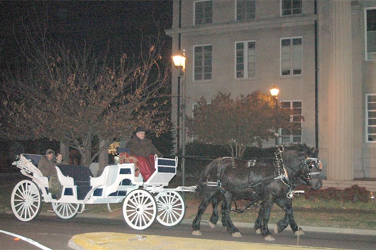 A couple takes a ride in the back of a horse wagon